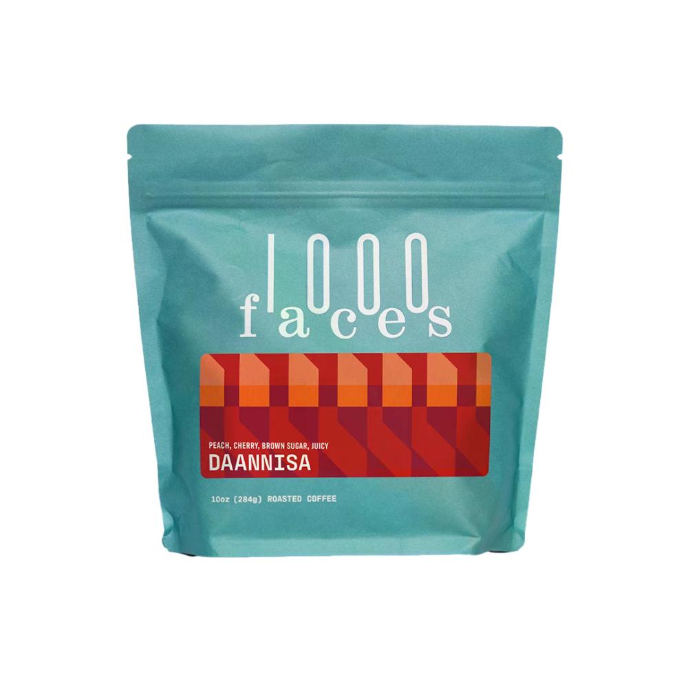 A 10oz stand-up pouch of 1000 Faces Daannisa roasted coffee on a solid white background. – 1000Faces Coffee main product