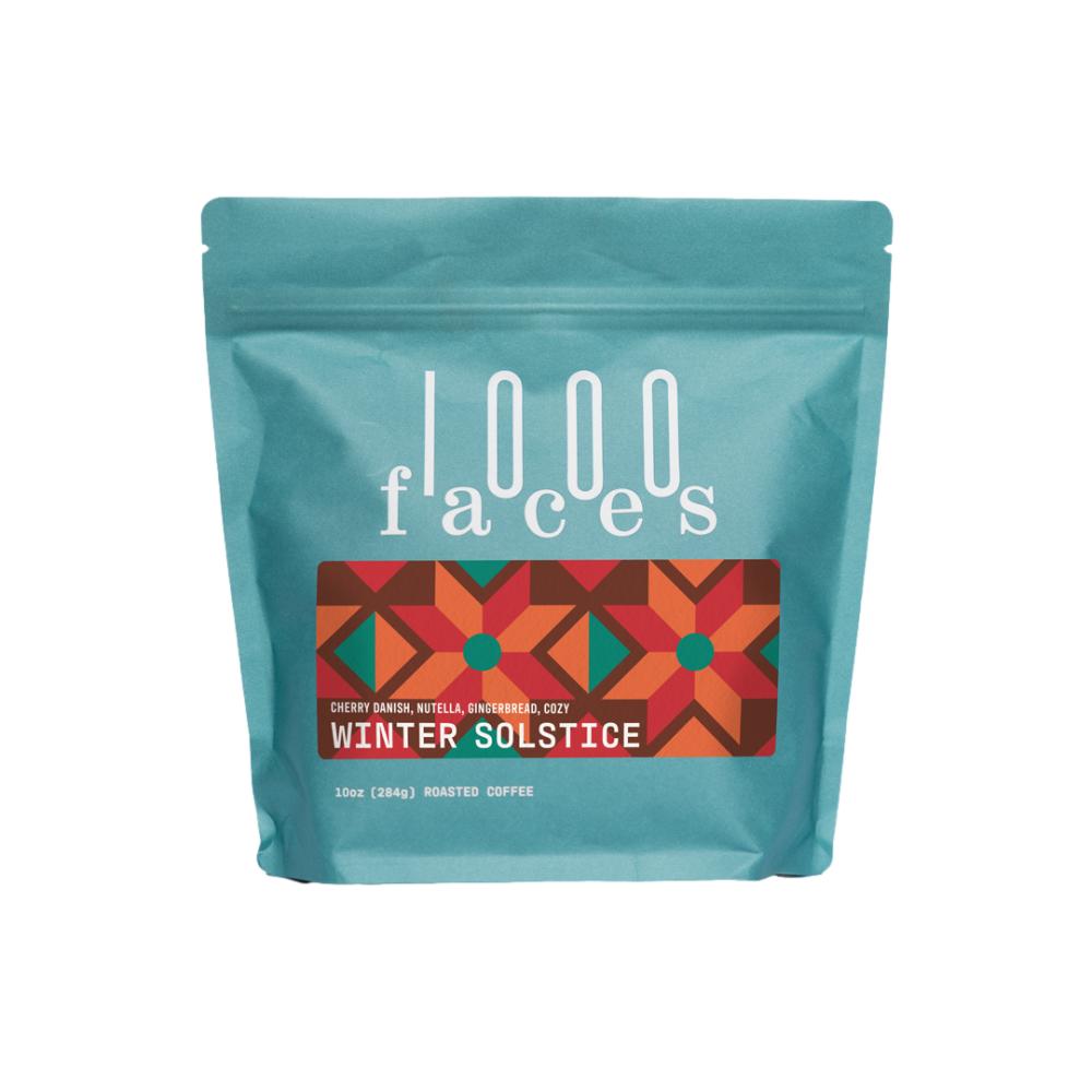 Teal coffee bag with '1000 Faces' branding and 'Winter Solstice' flavor label on a white background – 1000Faces Coffee main product