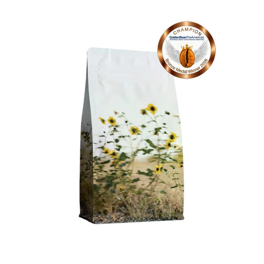 A stand-up pouch of Champion Organic Mental Health Support supplement featuring a printed design of sunflowers in a field, with a gold Champion logo badge in the top right corner.