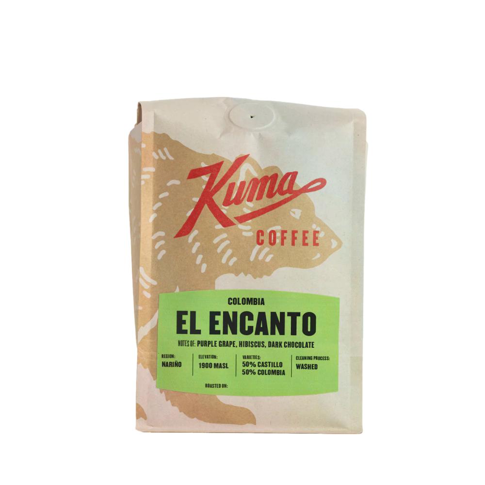 A stand-up coffee bag from Kuma Coffee, featuring a cream-colored design with a large red script logo and a bright green label that reads 'EL ENCANTO'.