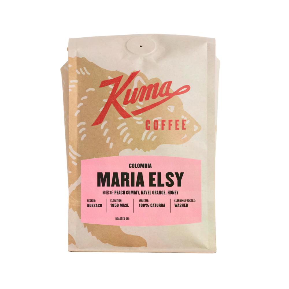 A bag of Kuma Coffee Maria Elsy Colombian coffee on a plain white background. The packaging is a natural kraft paper bag with a large pink label and red brand logo.