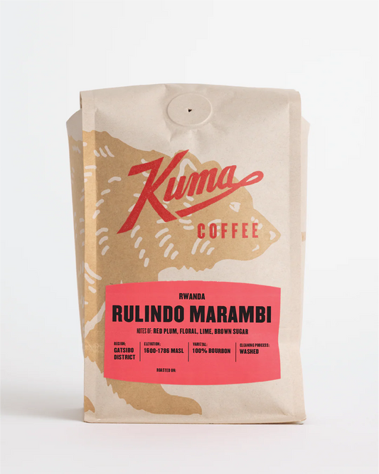 A stand-up coffee bag from Kuma Coffee on a clean white background. The packaging is cream-colored with a large tan bear silhouette and a bright pink label reading 'Rwanda Rulindo Marambi'.