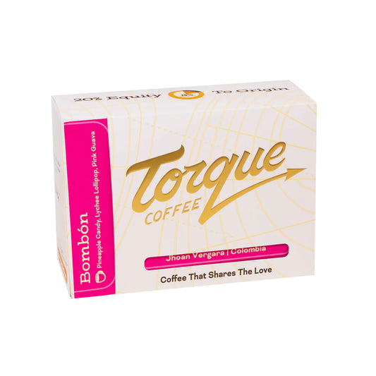 A box of Torque Coffee Bombón candy-coated lollipops, featuring a white box with gold script lettering and a bright pink side panel.