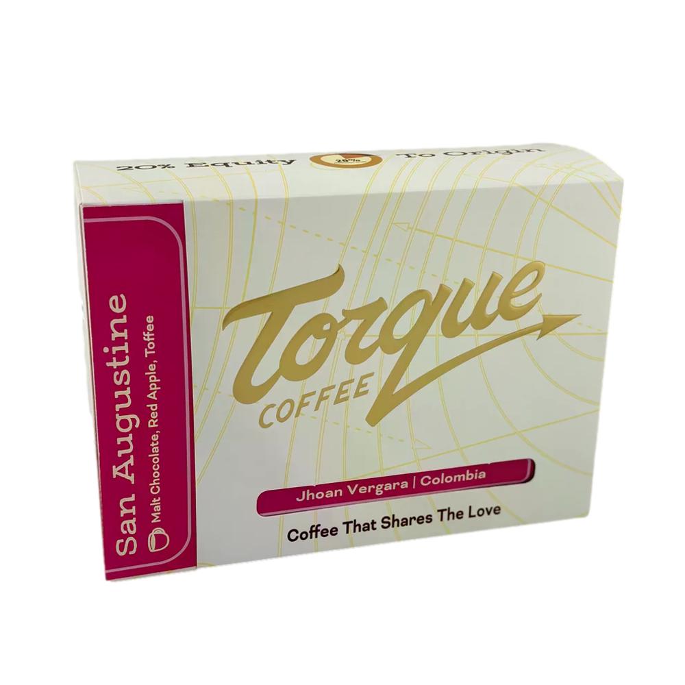 A box of Torque Coffee San Augustine coffee capsules, featuring a white box with gold script lettering and a magenta side panel. – Torque Coffees main product